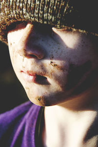 Close-up of boy wearing knit hat with muddy face