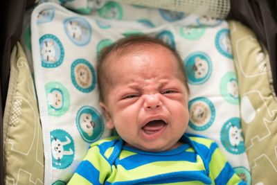 Portrait of cute baby crying on bed