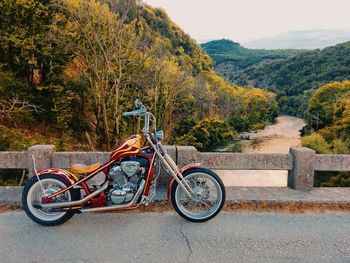 Custom chopper motorcycle on a bridge over a river in the mountains