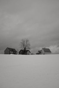 Houses on snowcapped field against sky during winter