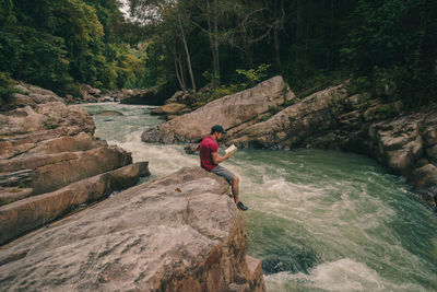 Man surfing on rock against trees