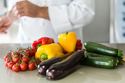 Midsection of male chef with various vegetables on kitchen island