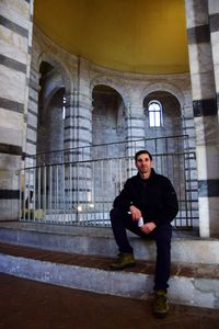 Full length of man sitting against building