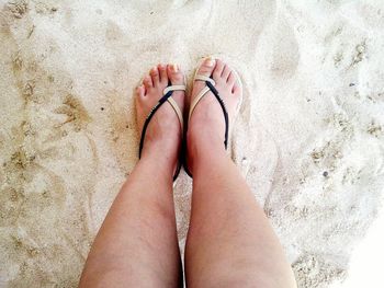 Low section of woman standing on sandy beach