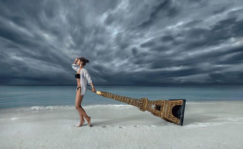 Woman standing at beach against sky