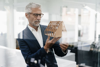 Mature businessman examining architectural model in office