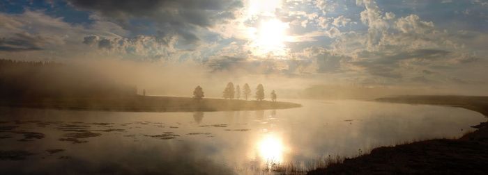 View of sun shining over lake during sunset