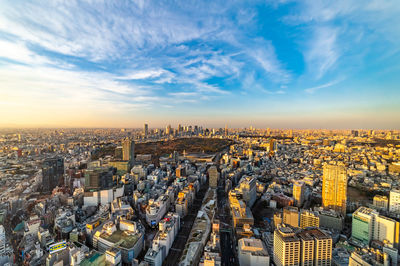 High angle view of city buildings against cloudy sky