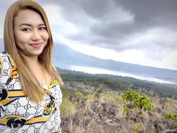 Portrait of smiling young woman against sky