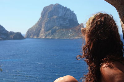 Rear view of woman in sea against mountains