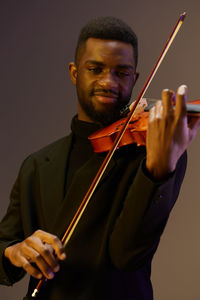 Midsection of man playing violin against white background