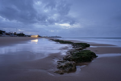 Scenic view of beach against sky at dusk