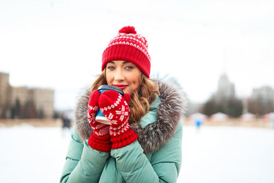 Portrait of smiling young woman wearing knit hat standing outdoors