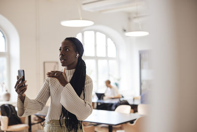 Businesswoman looking away while talking on video call through smart phone at office