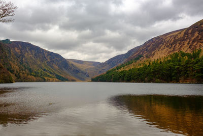 Scenic view of lake by mountains against sky