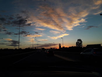 Cars on street against sky during sunset