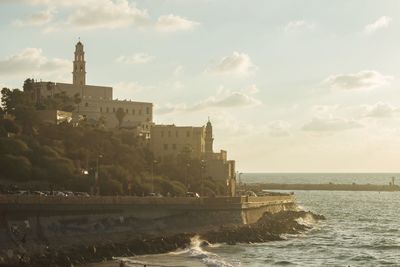 Buildings by sea against sky