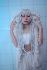 Portrait of young woman standing against wall