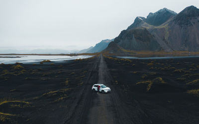 Cars on road by sea against sky