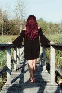 Rear view of woman standing against trees