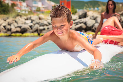 Cheerful teenage boy lying on a swimming board