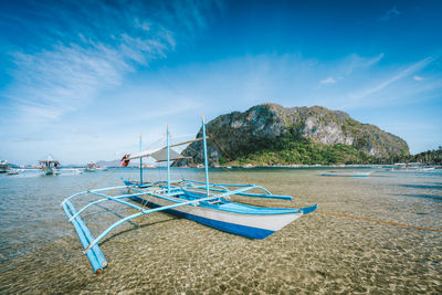 Fishing boats moored in sea against blue sky