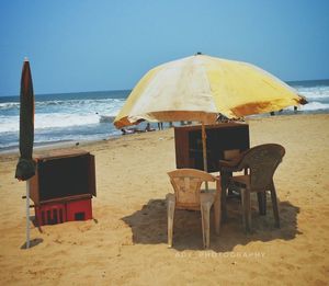 Chairs and tables on beach against clear sky