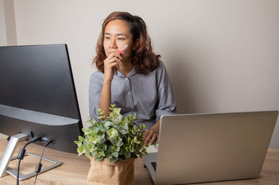 Young woman using phone while sitting on table