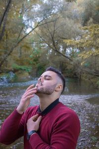 Portrait of young man drinking water in lake