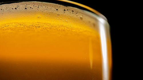 Close-up of beer glass against black background