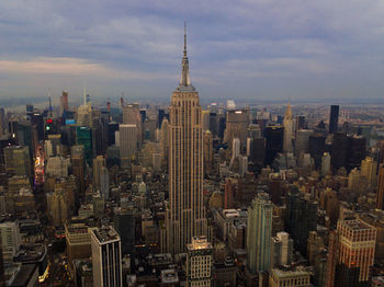 Aerial view of buildings in city against cloudy sky