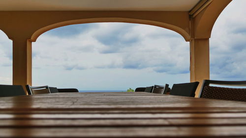 Surface level view of empty seats by sea against sky