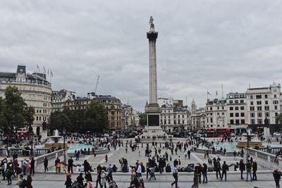 People at city square against cloudy sky