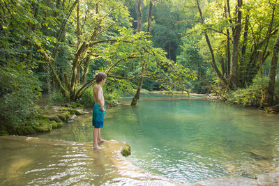 Full length of shirtless boy standing in water