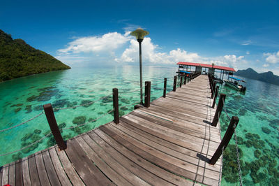 Pier on sea against cloudy sky