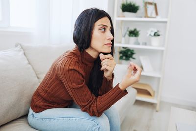 Portrait of young woman sitting on sofa at home