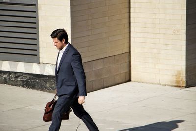 Full length of a young man standing against wall