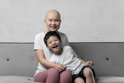 Portrait of happy friends sitting against wall