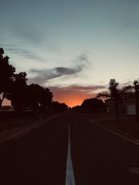 Empty road against sky at sunset