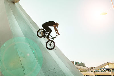 Man riding bicycle on built structure against sky