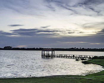 Pier over lake against sky during sunset