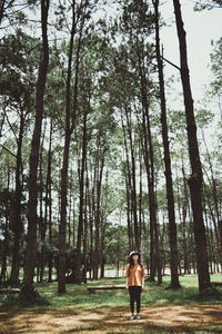 Woman standing by trees in forest