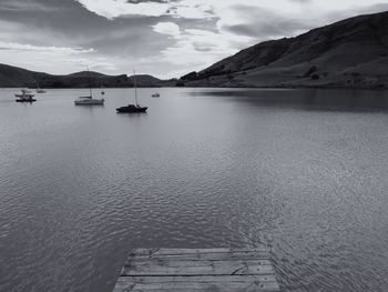 Boats in calm lake against mountain range