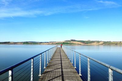 Pier over lake against blue sky