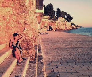 Smiling young woman sitting on steps during sunset