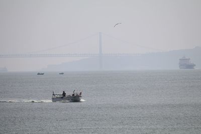 Boat in tagus river against 25 de abril bridge