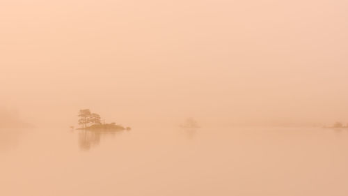 Scenic view of lake against sky at foggy weather