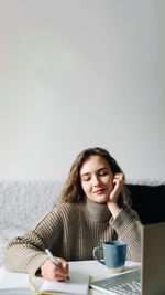 Portrait of young woman using mobile phone by sea