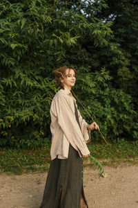 Side view of woman standing against trees