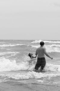 Father and son standing in sea against clear sky